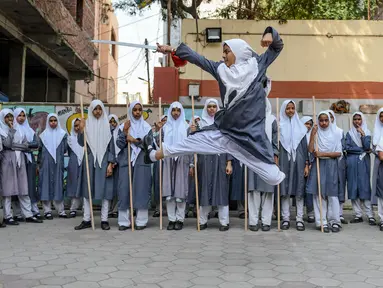 Seorang gadis muslim (tengah) memainkan pedang saat berlatih seni bela diri Vovinam untuk tampil dalam Hari Perempuan Internasional di sekolah menengah St Maaz, Hyderabad, India, Kamis (5/3/2020). Vovinam adalah seni bela diri menggunakan pedang dan tongkat asal Vietnam. (NOAH SEELAM/AFP)