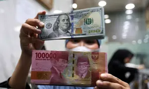 Sebelumnya, pada Selasa (5/5/2026), nilai tukar rupiah terhadap dolar AS bergerak melemah 11 poin atau 0,07 persen menjadi Rp17.405 per dolar AS. Tampak dalam foto, karyawan menunjukkan uang pecahan dolar Amerika Serikat (AS) dan rupiah di salah satu gerai penukaran mata uang asing, Jakarta, Rabu (5/5/2026). (Kapanlagi.com/Budy Santoso)