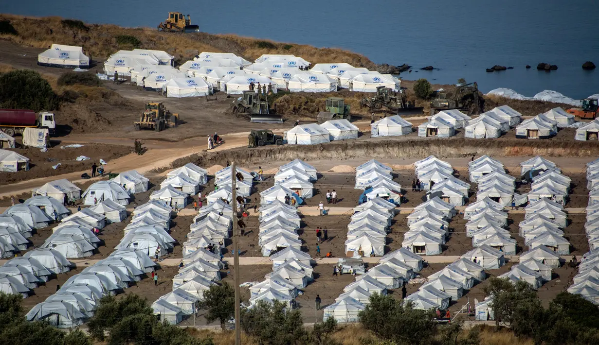 Alat berat beroperasi saat para migran berkumpul di kamp tenda sementara di Kara Tepe, Lesbos, Yunani, Kamis (17/9/2020). Lebih dari 5.000 pencari suaka kehilangan tempat tinggal sepekan setelah kebakaran menghanguskan kamp migran terbesar di Yunani, Kamp Moria. (AP Photo/Panagiotis Balaskas)