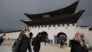 Pengunjung mengenakan masker berjalan di Gerbang utama Istana Gyeongbok, Seoul, Korea Selatan, Sabtu (22/2/2020). Sebagian besar infeksi corona ditelusuri ke rumah sakit dan sebuah gereja. (AP Photo/Lee Jin-man)