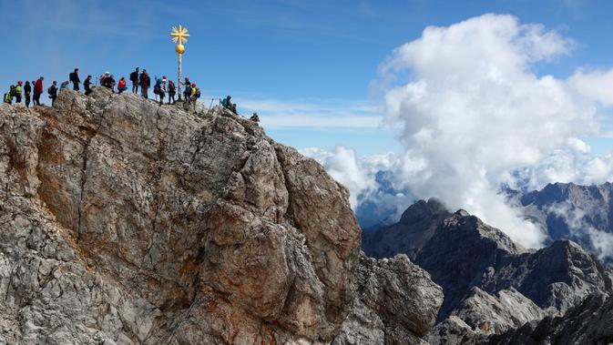 Orang-orang mengantre untuk mencapai puncak salib di puncak gunung tertinggi Jerman, Zugspitze, dekat Garmisch-Partenkirchen, Jerman pada 19 Agustus 2020. Setiap tahunnya gunung dengan ketinggian 2.962 meter tersebut membuat sekitar setengah juta pengunjung terpesona. (AP Photo/Matthias Schrader)