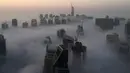 Saat gedung-gedung pencakar langit di selimuti kabut pagi di Kota Dubai, Uni Emirat Arab, Senin (5/12). Kota Dubai, terkenal dengan bangunan-bangunan mewah pencakar langit. Satu di antaranya adalah yang tertinggi di dunia, Burj Khalifa. (AFP/Rene Slama)