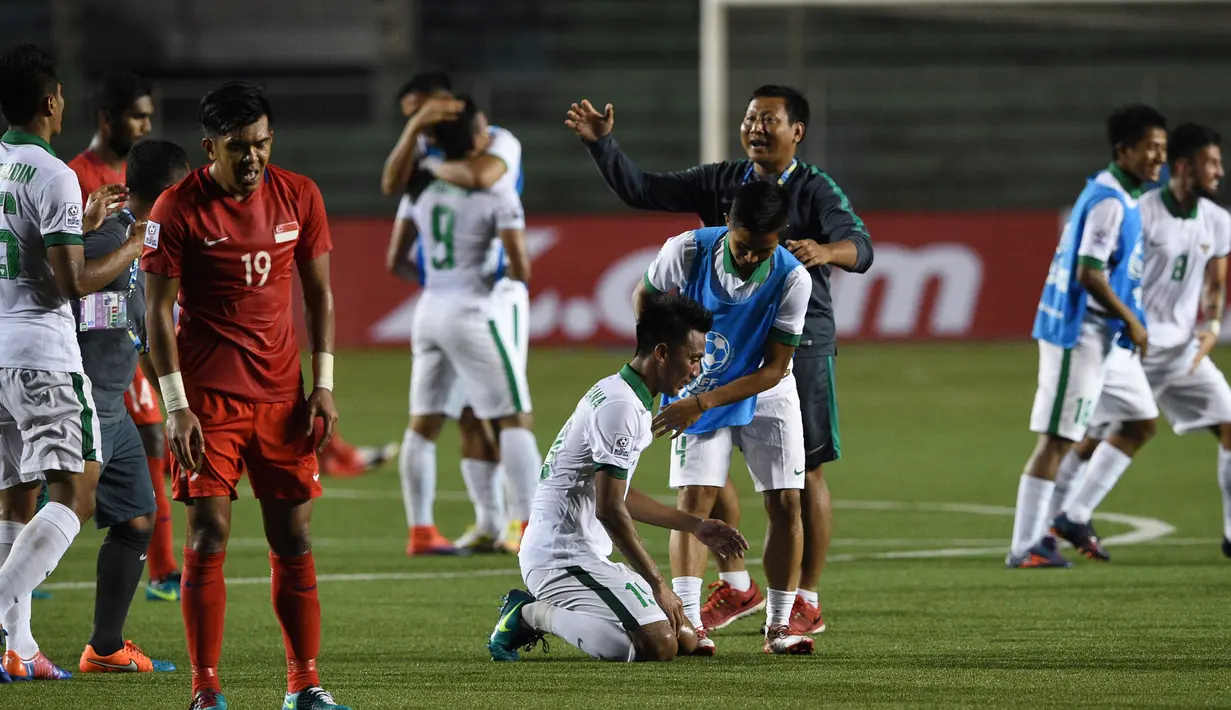 Pemain Singapura terlihat lemas sedangkan pemain Indonesia terlihat bergembira usai wasit meniup pluit akhir di laga hidup babak penyisihan grup di Piala AFF 2016, Manila, Jumat (25/11). Indonesia menang 2-1 atas Singapura. (AFP PHOTO / Ted Aljibe)