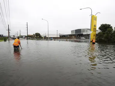 Para pekerja mencoba mensurvei tanah di bawah air banjir di Auckland, Selandia Baru, Rabu (1/2/2023). Peringatan hujan lebat untuk Auckland dicabut, meskipun keadaan darurat tetap berlaku untuk kota terbesar di negara itu setelah curah hujan dan banjir yang mencapai rekor. pada hari Jumat menewaskan empat orang dan menyebabkan gangguan yang meluas. (Brett Phibbs/New Zealand Herald via AP)
