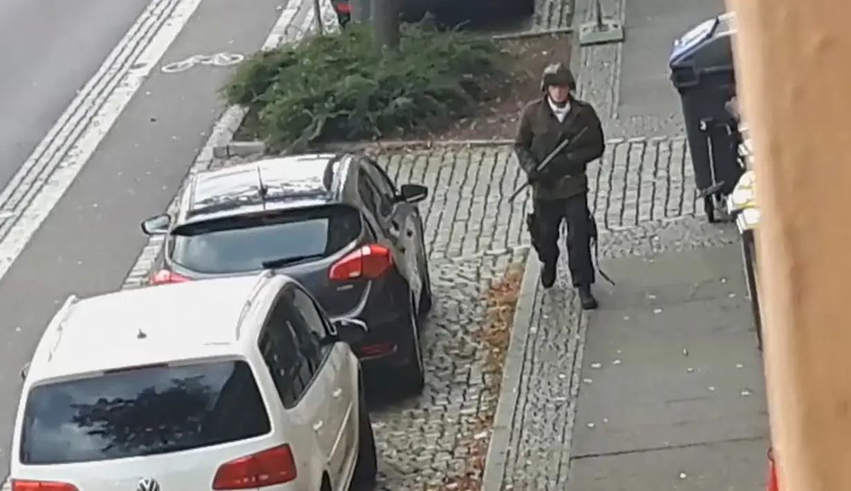 Seorang pria berjalan membawa senjata di jalanan Halle an der Saale, Halle, Jerman, Rabu (9/10/2019). Pelaku melarikan diri menggunakan mobil usai melancarkan aksinya. (Andreas Splett/ATV-Studio Halle/AFP)