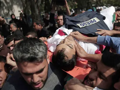 Pelayat membawa jasad seorang wartawan Palestina yang tewas ditembak tentara Israel saat meliput protes di perbatasan Gaza dengan Israel, Sabtu (7/4). Wartawan bernama Yasser Murtaja itu bekerja untuk kantor berita Ain Media. (AP Photo/Khalil Hamra)