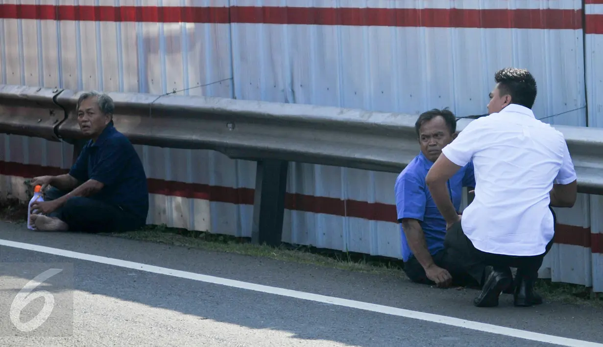 Pengendara mobil boks yang terbalik (kiri dan tengah) tampak syok dan terduduk lemas di bahu jalan tol, Jakarta, Senin (30/5). Sebuah mobil boks terbalik di KM 02 Tol Cawang arah Cililitan. (Liputan6.com/Yoppy Renato)