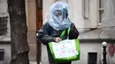 Seorang pria melindungi wajahnya dengan kantong plastik saat diberlakukannya lockdown untuk menghentikan penyebaran COVID-19 di jalanan Paris pada 21 Maret 2020. Masker dijadikan masyarakat pilihan untuk mencegah penyebaran virus corona yang terus meningkat di seluruh dunia. (FRANCK FIFE/AFP)