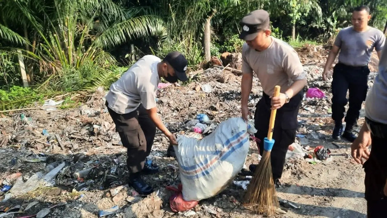 Personel Polda Riau memungut sampah di pinggir jalan Pekanbaru yang selama ini mencemari lingkungan.