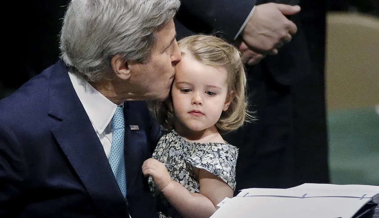 Menteri Luar Negeri AS John Kerry mencium cucunya Isabelle Dobbs-Higginson saat menandatangani surat Perjanjian Paris tentang perubahan iklim di Markas Besar PBB, Manhattan, New York, AS (22/4). (REUTERS / Carlo Allegri)