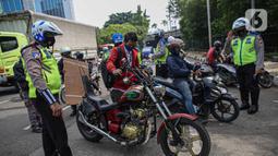 Petugas kepolisian lalu lintas memberhentikan pengendara motor saat Operasi Zebra Jaya 2020 di kawasan Cawang, Jakarta, Senin (26/10/2020). Operasi Zebra Jaya dilaksanakan pada 26 Oktober-8 November 2020 untuk menekan jumlah pelanggaran lalu lintas. (Liputan6.com/Faizal Fanani)