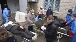 Jenazah disiapkan sebelum dimasukkan ke dalam kantong jenazah dan dimakamkan pada kuburan massal di pinggiran Mariupol, Ukraina, 9 Maret 2022. (AP Photo/Evgeniy Maloletka)