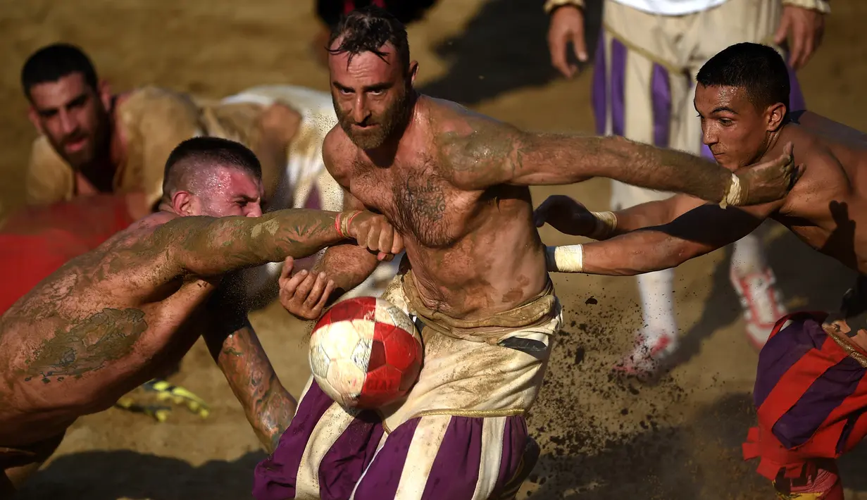 Pemain berebut bola saat pertandingan Calcio Storico Fiorentino di Piazza Santa Croce di Florence, Italia (24/6). Permainan ini selalu diselenggarakan di kota Florence, oleh karenanya sering disebut juga Calcio Fiorentino. (AFP Photo/Filippo Monteforte)