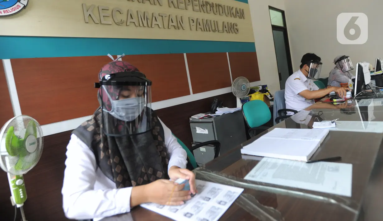 Petugas Dinas Kependudukan dan Catatan Sipil menggunakan pelindung wajah saat mengurus KTP-el di Kecamatan Pamulang, Tangerang Selatan, Rabu (3/6/2020). Sejumlah kantor pelayanan pemerintah melaksanakan protokol kesehatan yang ketat untuk memutus rantai penyebaran covid-19. (merdeka.com/Arie Basuki)