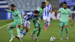 Pemain Real Sociedad Portu berebut bola dengan pemain Real Madrid Vinicius Junior dan Sergio Ramos pada pertandingan La Liga di Stadion Anoeta, San Sebastian, Spanyol, Minggu (21/6/2020). Real Madrid memuncaki klasemen sementara La Liga usai mengalahkan Real Sociedad. (AP Photo/Alvaro Barrientos)