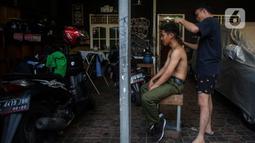 Warga mencukur rambut di Perumahan Padat Penduduk kawasan Kuningan Jakarta, Kamis (1/7/2021). Kasus corona di Jakarta dalam beberapa hari terakhir terus melonjak tinggi. (Liputan6.com/Johan Tallo)