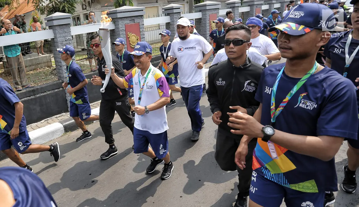 Direktur SDM dan Umum Askrindo Firman Berahima membawa api obor Asian Games 2018 dengan berlari sejauh 500 meter melalui rute RSPAD Gatot Subroto - Hotel Borobudur Jakarta, Kamis (16/8).(Liputan6.com/Faizal Fanani)