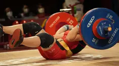 Hoang Thi Duyen dari Vietnam terjatuh saat bertanding di cabang angkat besi 59kg putri Olimpiade Tokyo 2020, Selasa (27/7/2021). (Foto: AP/Luca Bruno)