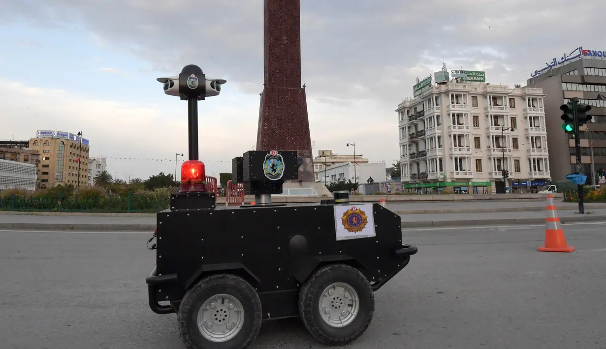 Sebuah robot polisi Tunisia berpatroli selama kebijakan penguncian (lockdown) di sepanjang Avenue Habib Bourguiba, pusat ibu kota Tunis, Rabu (1/4/2020). Robot ini dilengkapi dengan deteksi termal (temperatur tubuh manusia) dan kemampuan video audio secara real time. (FETHI BELAID/AFP)