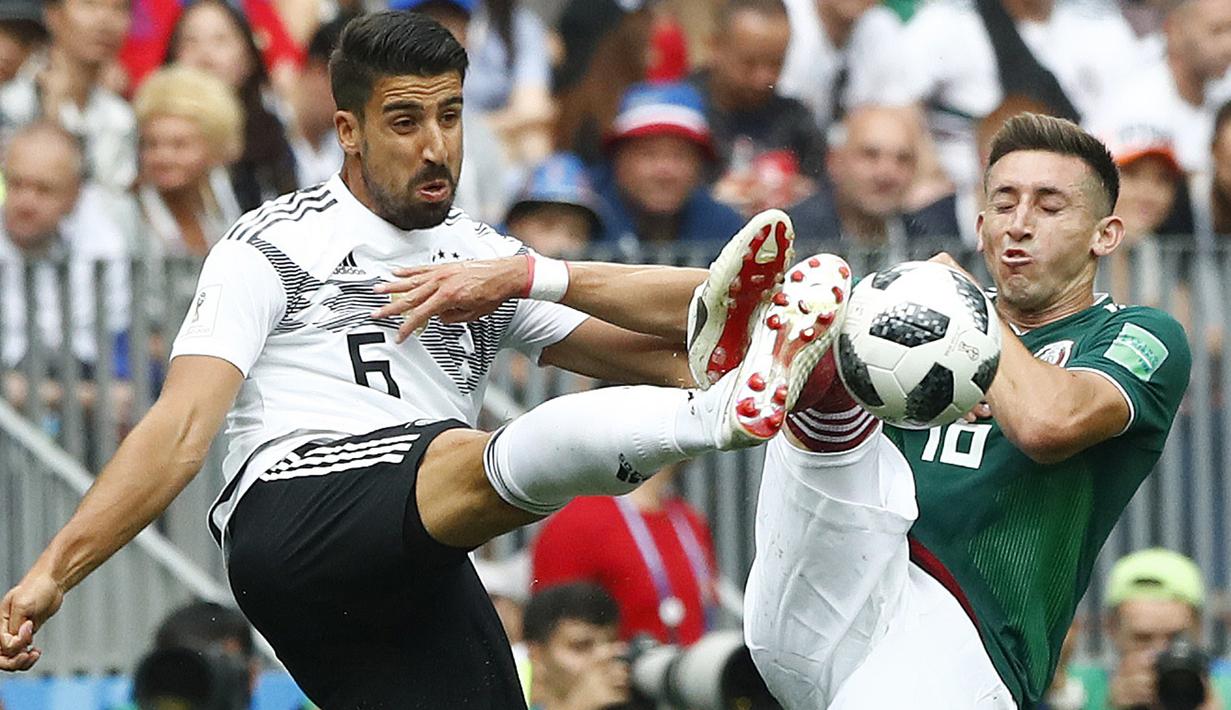 Gelandang Jerman, Sami Khedira, berebut bola dengan bek Meksiko, Hector Herrera, pada laga Grup F Piala Dunia di Stadion Luzhniki, Moskow, Minggu (17/6/2018). Meksiko menang 1-0 atas Jerman. (AP/Matthias Schrader)