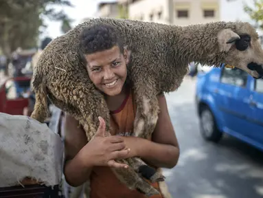 Seorang anak tersenyum setelah membeli seekor domba untuk perayaan Idul Adha di sebuah pasar di pinggiran Rabat, Maroko, Kamis (30/7/2020). (AP Photo/Mosaab Elshamy)