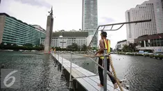 Pekerja membawa penyanggah di kolam Bundaran HI, Jakarta, Rabu (23/3). Pemasangan penyanggah bertujuan untuk menahan Tugu Selamat Datang dari getaran saat Bor Antareja proyek Mass Rapid Transit (MRT) melintas dibawahnya. (Liputan6.com/Faizal Fanani)