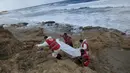 Kelompok Bulan Sabit Merah Libya membawa kantong mayat berisi jenazah, diduga imigran yang tewas usai kapal mereka tenggelam, di pantai Khoms, sebelah timur Tripoli, Minggu (25/10). Sedikitnya 40 jasad ditemukan di pantai Libya. (REUTERS/Ismail Zitouny)