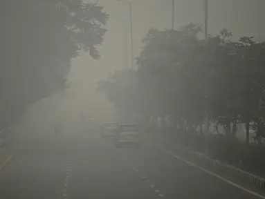 Kendaraan bermotor menembus kabut asap pekat yang menyelimuti jalan di New Delhi, Minggu (3/10/2019). Ibu Kota dari India tersebut sedang dilanda polusi udara yang sangat buruk sekaligus beracun pekan ini. (Photo by Sajjad  HUSSAIN / AFP)