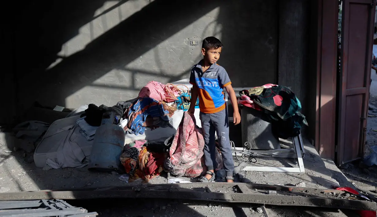 Seorang anak pengungsi Palestina berdiri di dalam rumah yang menjadi sasaran serangan Israel di kamp pengungsi Maghazi, Jalur Gaza Tengah pada Kamis 21 Mei 2026. (Eyad Baba/AFP)