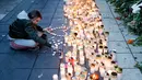 Seorang wanita menyalakan lilin di lokasi terjadinya serangan truk di Stockholm, Swedia, Minggu (9/4). Sebuah truk yang dibajak menabrakkan diri ke kerumunan pejalan kaki pada Sabtu (8/4) dan menewaskan empat orang. (AP Photo / Markus Schreiber)