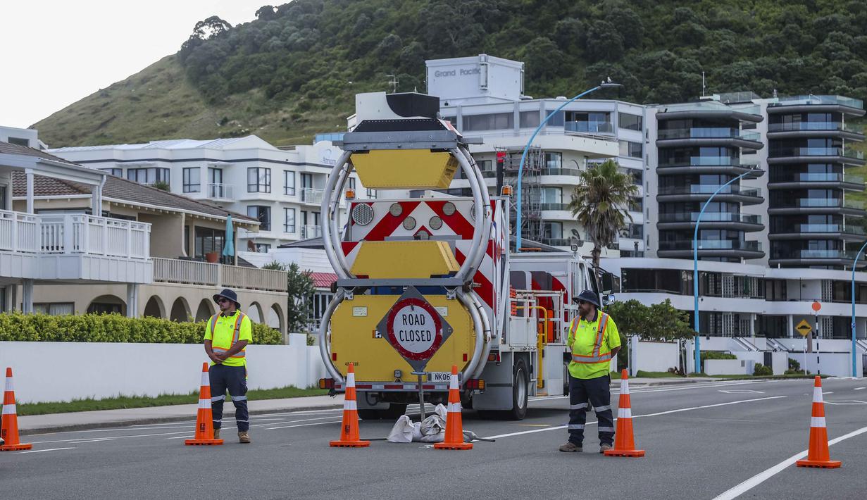 Layanan darurat setempat terus berupaya memastikan tidak ada lagi orang yang terjebak di area tersebut. Tampak dalam foto, petugas darurat menutup jalan setelah tanah longsor sementara pencarian sedang dilakukan oleh layanan darurat setempat untuk orang hilang di Gunung Maunganui, Tauranga, Selandia Baru pada Kamis 22 Januari 2026. (DJ MILLS/AFP)