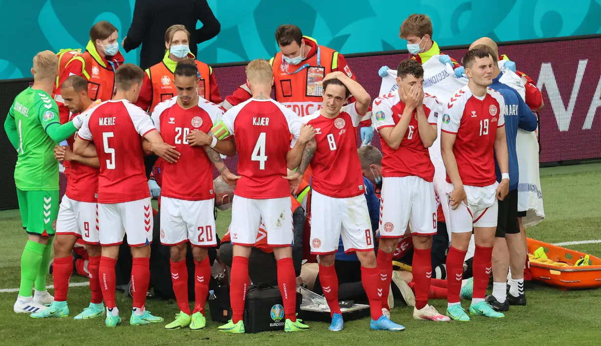 Tim Denmark dengan arahan kapten mereka, Simon Kjaer berjasa membuat pagar untuk mengerubungi Christian Eriksen agar Eriksen yang terkulai lemas tidak menjadi sorotan media. (Foto: AFP/Pool/Wolfgang Ratty)