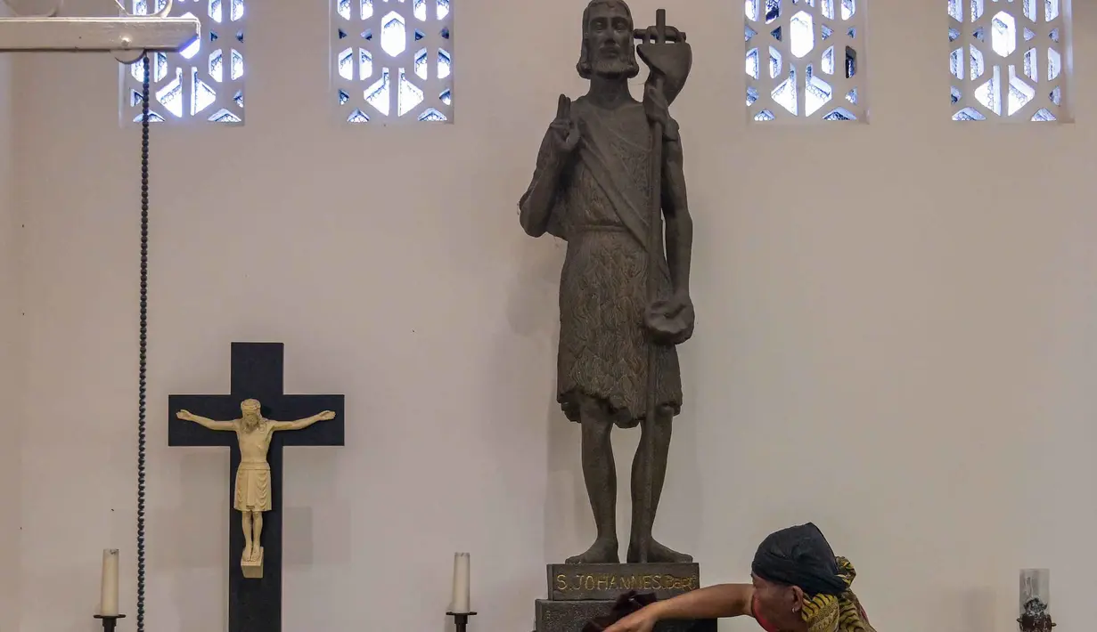 Kegiatan ini bertujuan memperingati kelahiran Yesus Kristus. Tampak dalam foto, seorang pekerja membersihkan patung Santo Yohanes Pembaptis di Katedral Hati Kudus Yesus, yang dikenal secara lokal sebagai gereja "Hati Kudus Yesus", selama persiapan Misa Natal di Surabaya, Jawa Timur, pada Selasa 23 Desember 2025. (JUNI KRISWANTO/AFP)