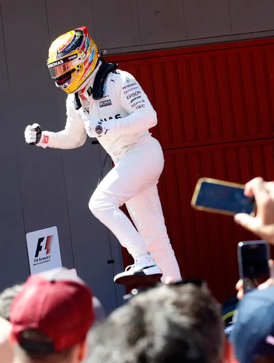 Pembalap Mercedes, Lewis Hamilton berselebrasi setelah memenangi balapan F1 GP Spanyol di Sirkuit Catalunya, Minggu (14/5). Hamilton mencatatkan waktu tercepat, satu jam 35 menit 56,497 detik setelah melahap 66 putaran lintasan. (AP Photo/Manu Fernandez)