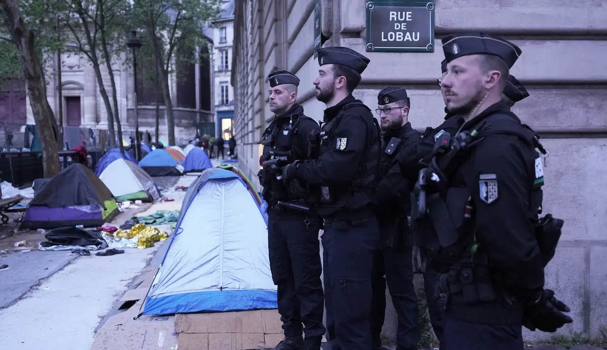 Petugas polisi berdiri di kamp darurat selama operasi pembersihan di Paris, Selasa (30/4/2023). (AP Photo/Michel Euler)