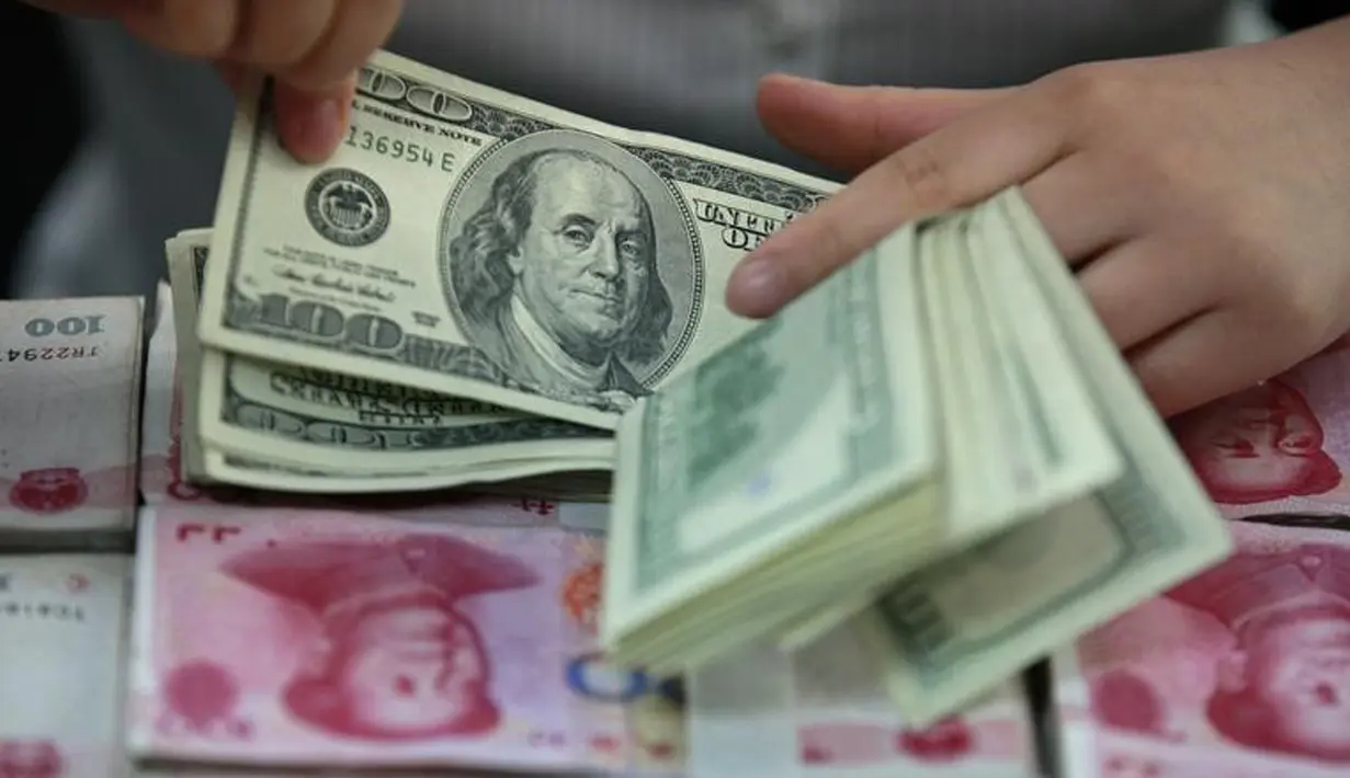 Teller menghitung uang pecahan 100 Dollar di atas uang yuan China di sebuah bank di Huaibei, China, 11 Agustus 2015. Langkah Bank Sentral China menurunkan nilai tukar yuan terhadap dolar AS langsung membuat pelaku pasar ketakutan. (REUTERS/Stringer)
