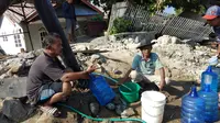 Korban gempa Palu menikmati air bersih melalui pipa PDAM yang bocor. (Liputan6.com