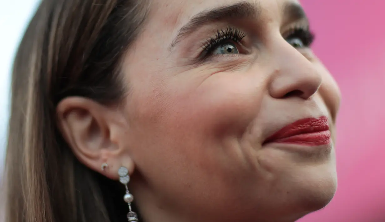 Emilia Clarke melengkapi penampilannya dengan sepasang anting-anting mutiara yang menjuntai dan meninggikan badannya dengan sepatu hak tinggi berwarna hitam yang simpel. (LOU BENOIST / AFP)