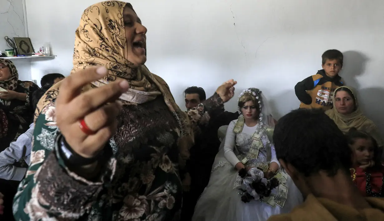 Seorang wanita menari saat pengantin wanita Heba (kanan) dan pengantin pria Ahmed (kiri) duduk di tengah perayaan pernikahan di Raqqa, Suriah (27/10). Kini ISIS sudah berhasil ditumpas dari Kota Raqqa. (AFP Photo/Delil Souleiman)