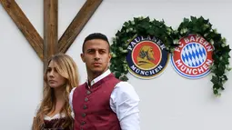 Gelandang Bayern Munchen, Thiago Alcantara bersama sang istri, Julia Vigas, mengenakan gaun tradisional Bavaria saat menikmati akhir dengan mengunjungi festival bir tahunan Oktoberfest di Munich, Jerman, Minggu (7/10). (Christof STACHE / AFP)