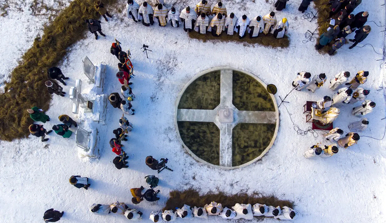 Pendeta Kristen Ortodoks Rusia melakukan kebaktian memberkati air es Sungai Tura saat perayaan Epiphany tradisional di Biara Tritunggal Mahakudus, Tyumen, Rusia, 18 Januari 2022. Penganut Kristen Ortodoks Rusia merayakan Epiphany dengan membenamkan diri dalam air dingin. (AP Photo/Sergei Rusanov)