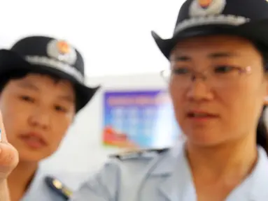 Petugas BPOM China memeriksa vaksin rabies di Pusat Pengendalian dan Pencegahan Penyakit di Huaibei, provinsi Anhui, Selasa (24/7). Otoritas China menginvestigasi skandal produksi vaksin rabies ilegal yang telah menimbulkan kepanikan masyarakat. (AFP)