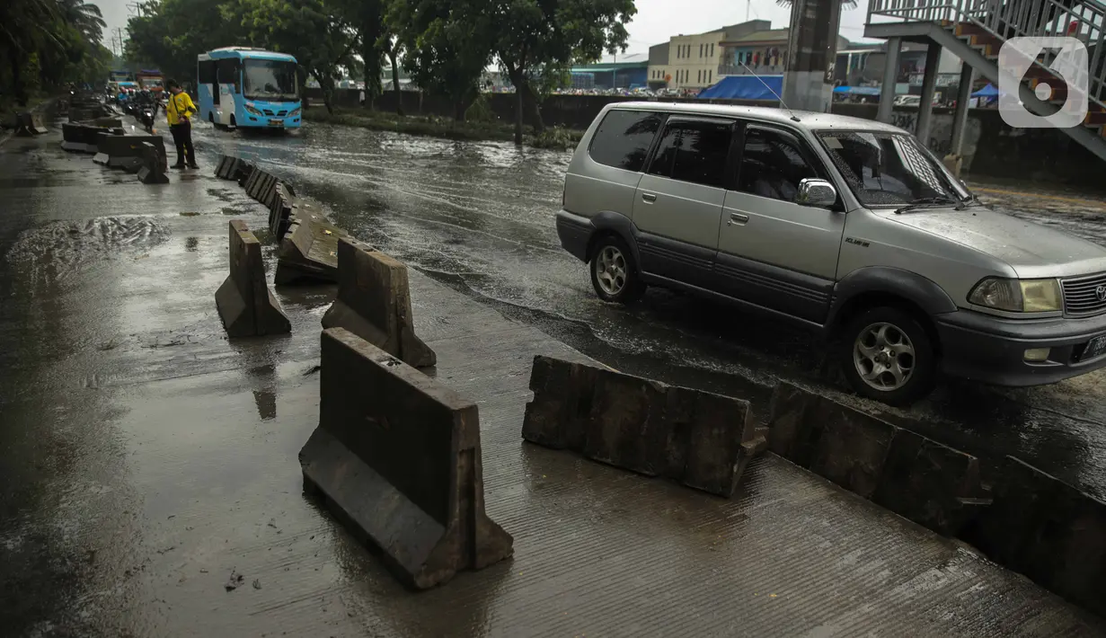 Kendaraan melintas dekat separator busway yang berserakan pascabanjir di Jalan Daan Mogot, Cengkareng, Jakarta, Jumat (3/1/2020). Separator busway tersebut berantakan akibat banjir yang menerjang sejak kemarin. (Liputan6.com/Faizal Fanani)