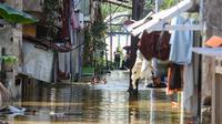 Warga beraktifitas saat banjir merendam pemukiman di Jalan Pirus, Kelurahan Bidara Cina, Jatinegara, Jakarta Timur, Minggu (6/7/2025). (merdeka.com/Arie Basuki)