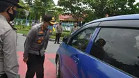 Personel Polda Riau mengecek pengemudi mobil terkait penerapan protokol kesehatan. (Liputan6.com/M Syukur)
