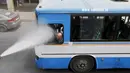 Seorang sopir bus disemprot oleh personel dinas Kota Amman menggunakan sprinkler air untuk mengurangi efek dari gelombang panas di Yordania, Senin(3/8/2015). (REUTERS/Muhammad Hamed)