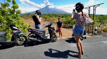 Sejumlah turis mengabadikan pemandangan erupsi Gunung Agung di Kabupaten Karangasem, Bali, Jumat (6/7). Erupsi Gunung Agung mengundang banyak perhatian warga dan wisatawan. (AFP FOTO / Sonny Tumbelaka)