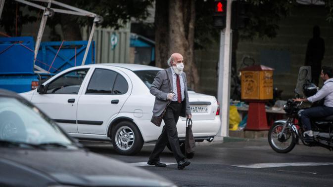Seorang pria dengan masker menyeberangi jalan di pusat Kota Teheran, 28 Juni 2020. Presiden Iran Hassan Rouhani pada Minggu (28/6) mengatakan mengenakan masker di tempat umum akan menjadi wajib mulai pekan depan di tengah meningkatnya kasus dan kematian akibat COVID-19. (Xinhua/Ahmad Halabisaz)