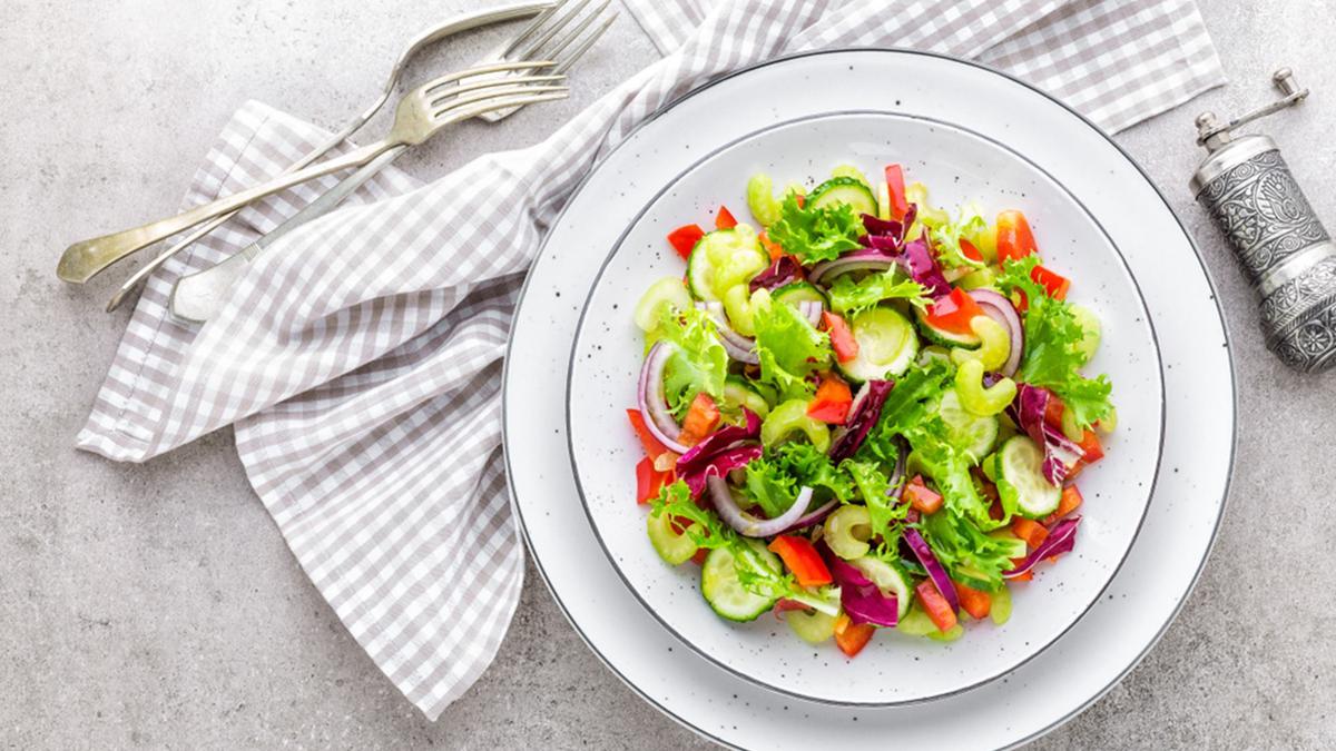 Semangkuk salad sayur segar dengan kombinasi selada, wortel, tomat, dan jagung manis, disajikan dengan dressing lemon segar