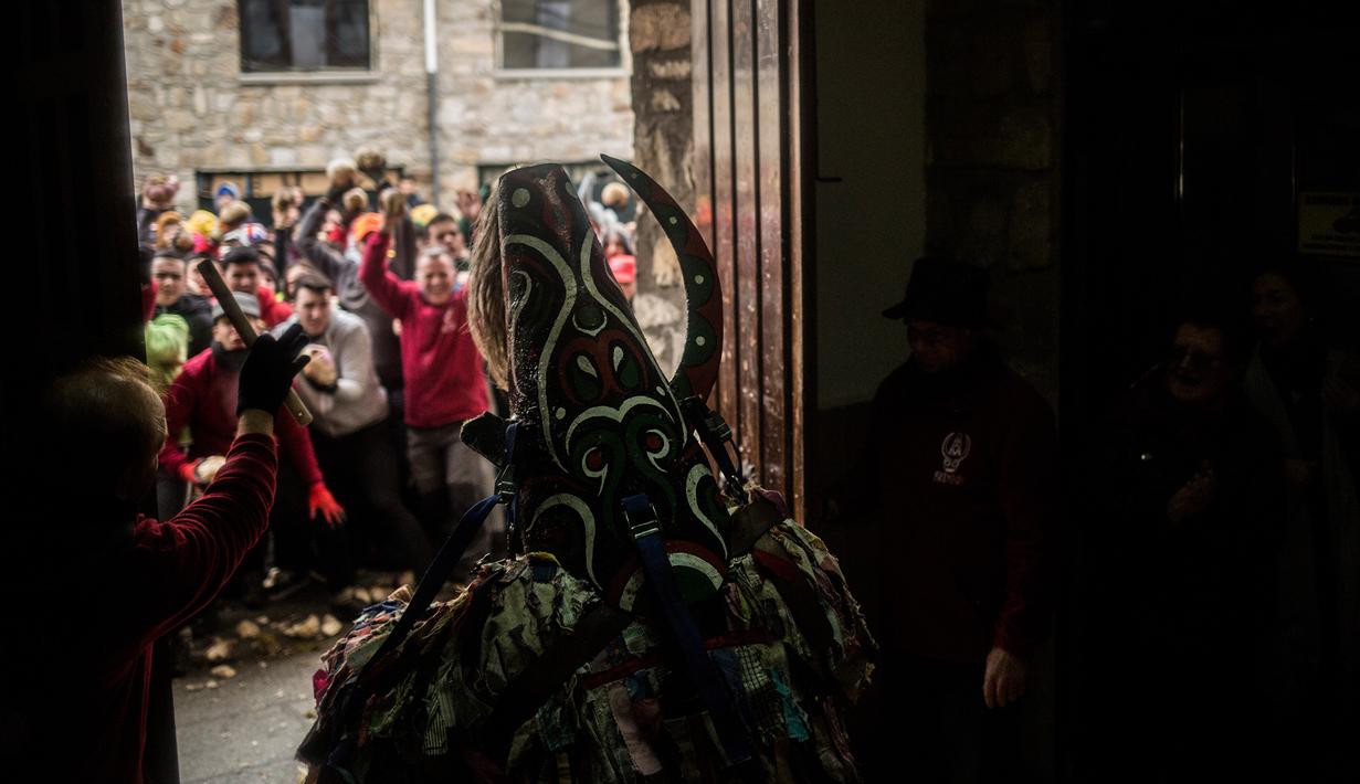 Orang-orang melempari seorang pria berkostum ala setan dengan sayuran lobak selama Festival Jarramplas di kota Piornal, Spanyol, Sabtu (19/1). Jarramplas memakai kostum dari kain warna-warni dilengkapi topeng bertanduk dan hidung panjang (AP/Javier Fergo)